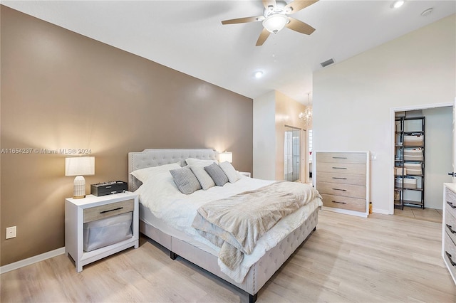 bedroom featuring light hardwood / wood-style flooring, ceiling fan with notable chandelier, and vaulted ceiling