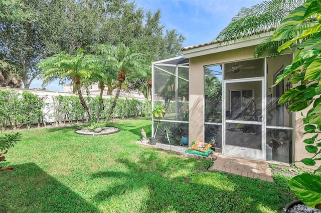 view of yard featuring ceiling fan and glass enclosure