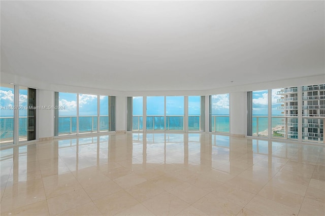 tiled empty room featuring a wall of windows and a water view