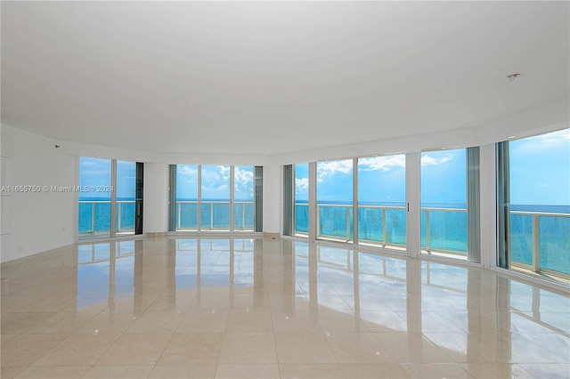 unfurnished room featuring light tile patterned floors, expansive windows, and a water view