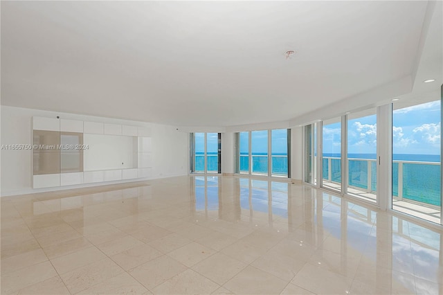 tiled spare room featuring a water view, floor to ceiling windows, and a healthy amount of sunlight