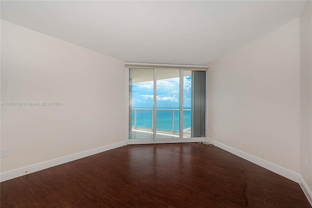 empty room featuring hardwood / wood-style flooring, floor to ceiling windows, and a water view