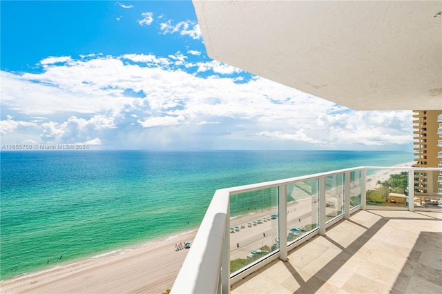 balcony with a water view and a view of the beach