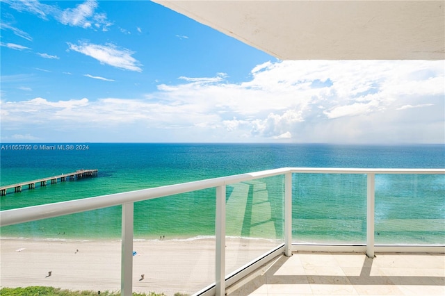 balcony featuring a view of the beach and a water view