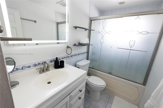 full bathroom featuring tile patterned flooring, vanity, toilet, and bath / shower combo with glass door