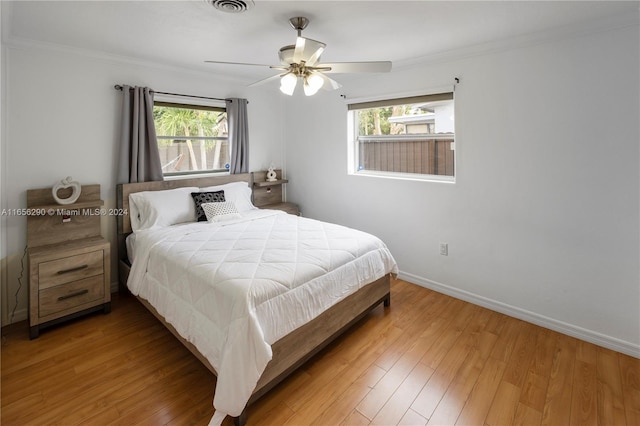 bedroom with ornamental molding, hardwood / wood-style floors, and ceiling fan