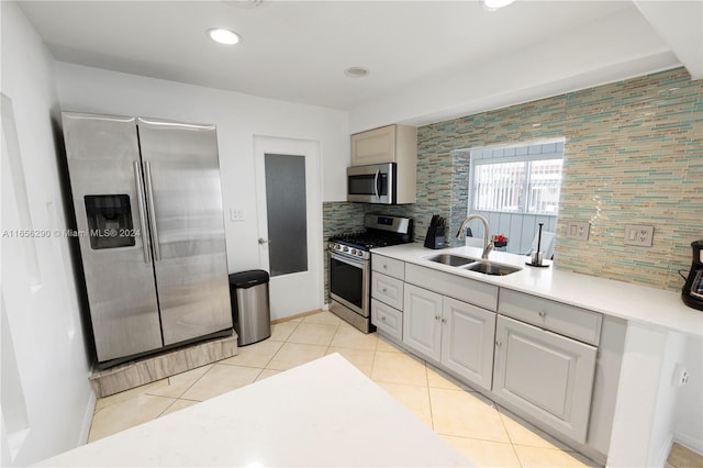 kitchen featuring appliances with stainless steel finishes, tasteful backsplash, sink, and light tile patterned flooring