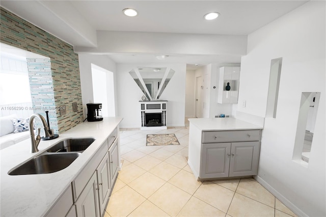 kitchen featuring gray cabinetry, light tile patterned floors, tasteful backsplash, and sink