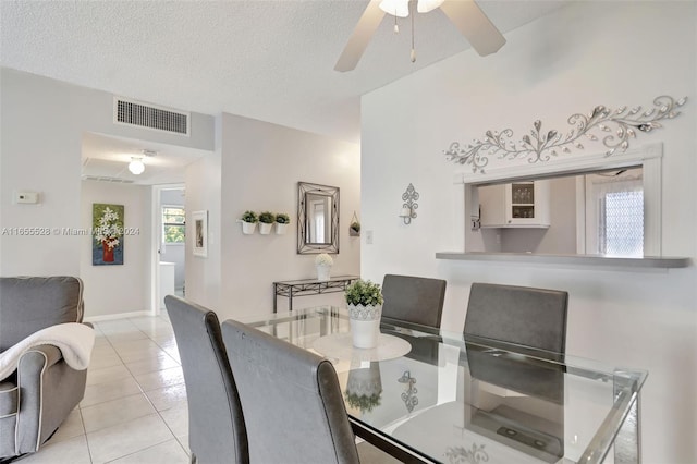 dining room featuring ceiling fan, light tile patterned floors, and a textured ceiling