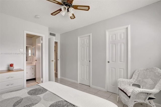 tiled bedroom featuring a textured ceiling, ceiling fan, multiple closets, and connected bathroom