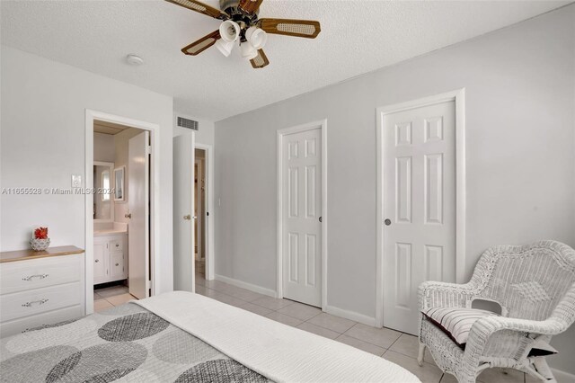 3501 NW 47th Ave Unit 516, Lauderdale Lakes, FL 33319 - bedroom featuring light tile patterned flooring, ensuite bathroom, baseboards, ceiling fan, and a textured ceiling