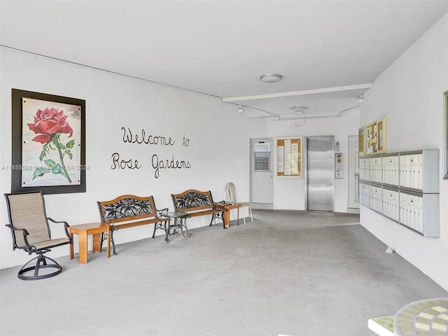 sitting room featuring mail boxes, elevator, and concrete flooring