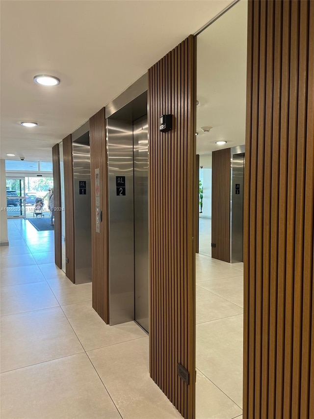 corridor with light tile patterned floors, elevator, and a wall of windows