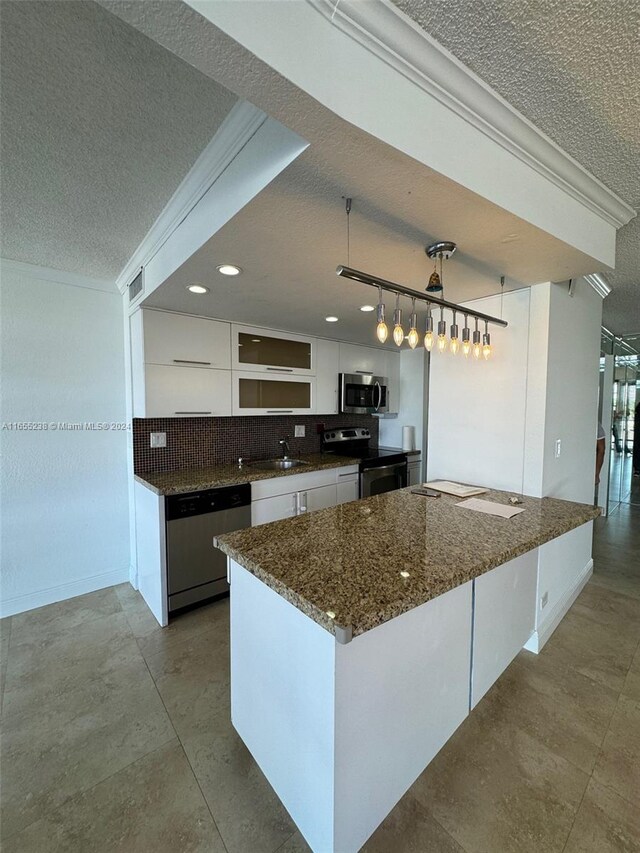 kitchen with dark stone countertops, appliances with stainless steel finishes, white cabinetry, sink, and a textured ceiling