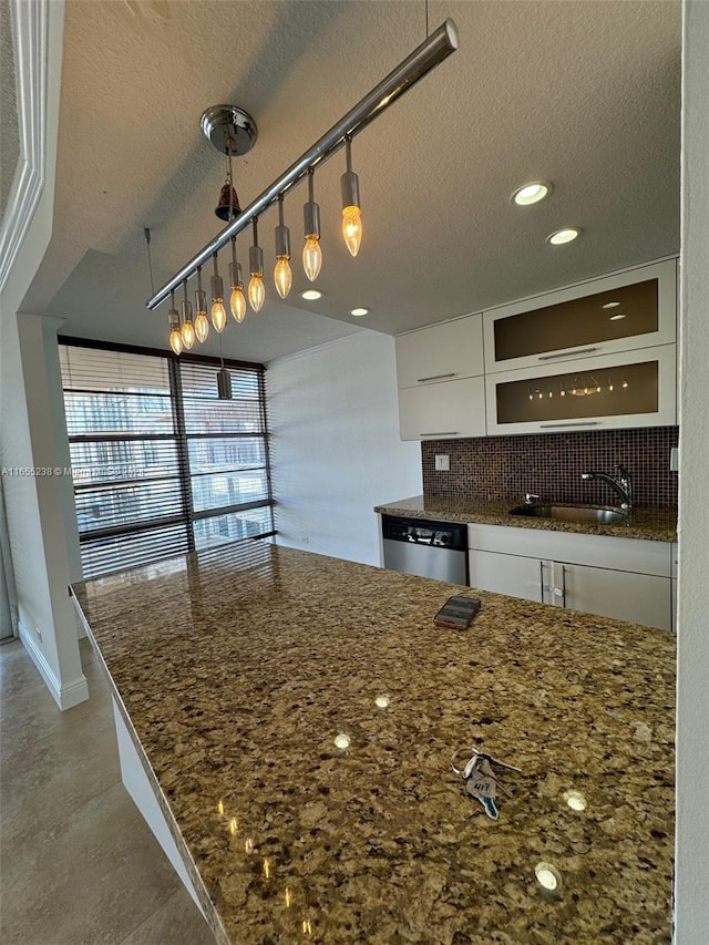 kitchen featuring stainless steel dishwasher, dark stone counters, white cabinetry, and a textured ceiling