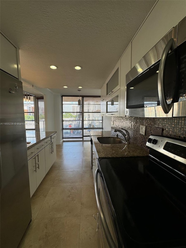 kitchen with appliances with stainless steel finishes, dark stone counters, white cabinetry, and sink