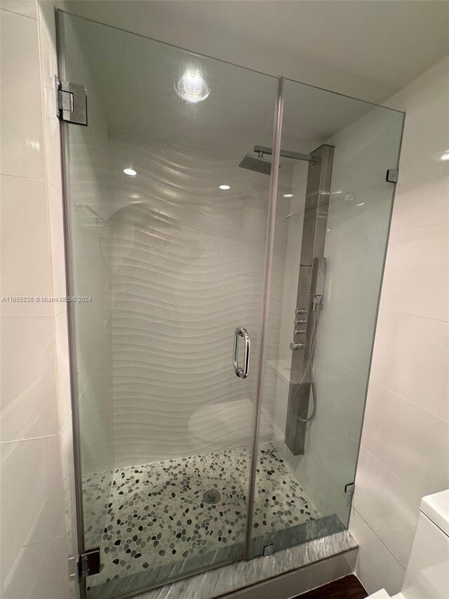 bathroom with tile walls, toilet, and an enclosed shower