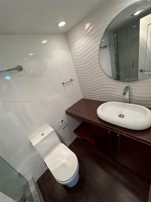 bathroom with hardwood / wood-style floors, walk in shower, toilet, and vanity