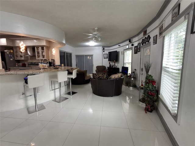 tiled living room featuring ceiling fan and sink