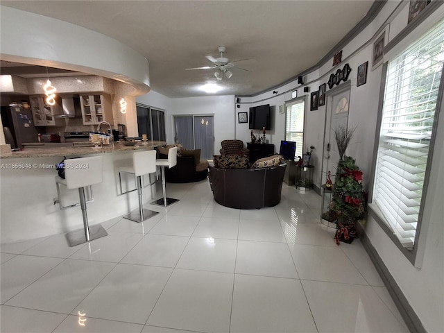 tiled living room with ceiling fan and sink