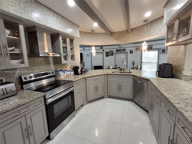 kitchen featuring wall chimney exhaust hood, light tile patterned floors, beam ceiling, stainless steel appliances, and sink