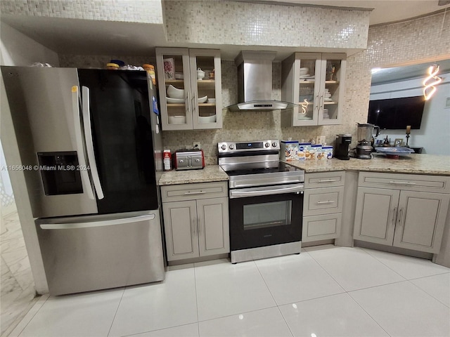 kitchen with wall chimney exhaust hood, appliances with stainless steel finishes, gray cabinets, and light tile patterned flooring