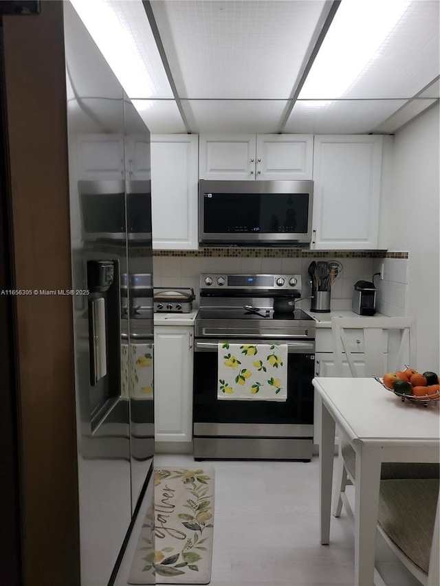 kitchen featuring stainless steel appliances, white cabinets, and tasteful backsplash