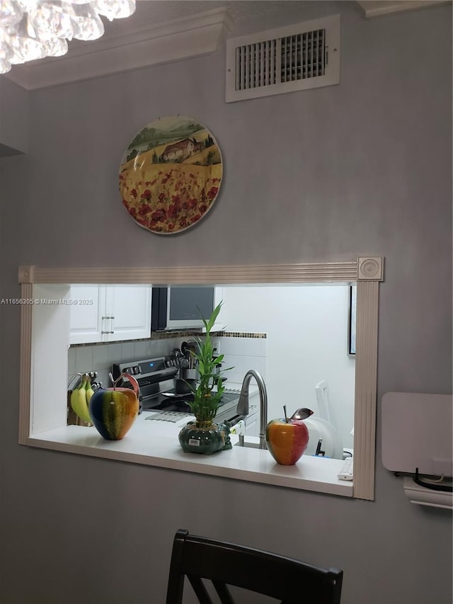 interior details featuring sink, electric range, backsplash, and white cabinets