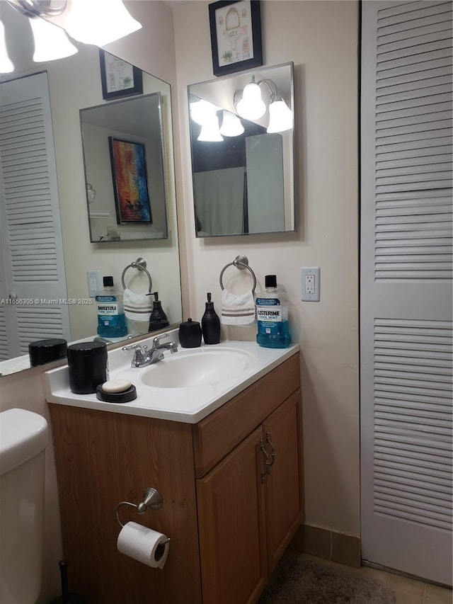 bathroom with toilet, vanity, and tile patterned floors