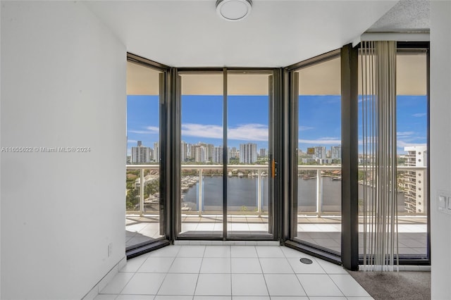 tiled empty room featuring a wall of windows and a water view