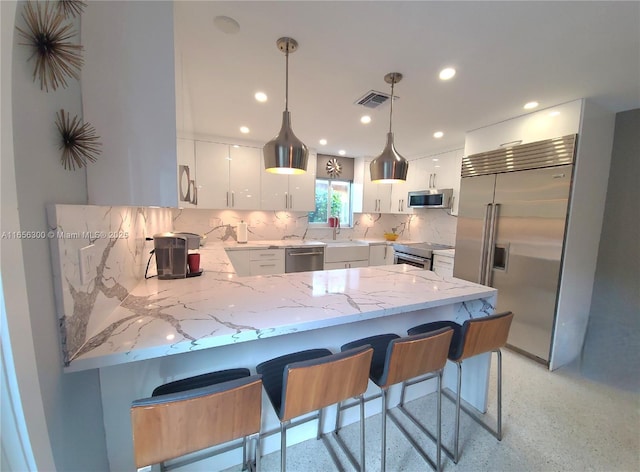 kitchen with white cabinetry, decorative light fixtures, kitchen peninsula, and appliances with stainless steel finishes