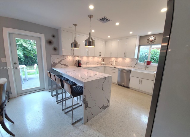 kitchen with a kitchen bar, dishwasher, kitchen peninsula, pendant lighting, and white cabinets