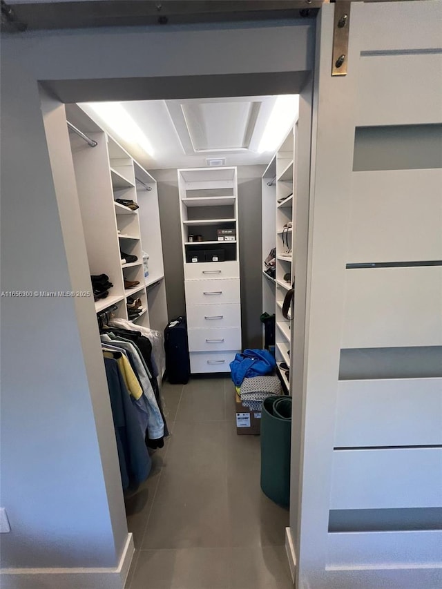 spacious closet with tile patterned floors and a barn door