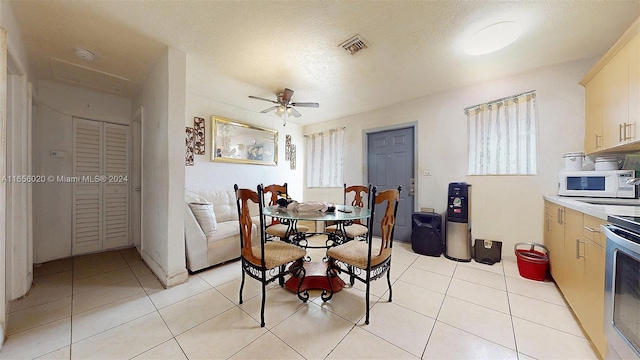 dining space with a textured ceiling, light tile patterned floors, and ceiling fan