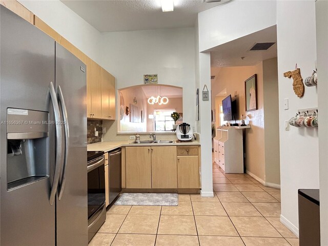 kitchen featuring a textured ceiling, light brown cabinetry, sink, appliances with stainless steel finishes, and light tile patterned flooring