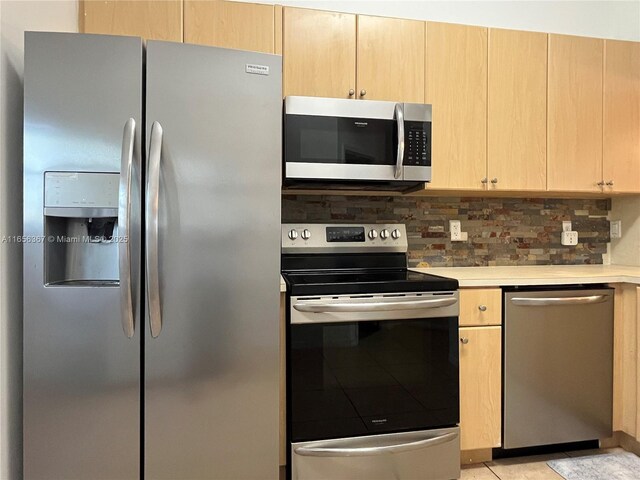 kitchen featuring appliances with stainless steel finishes, light tile patterned flooring, backsplash, and light brown cabinets