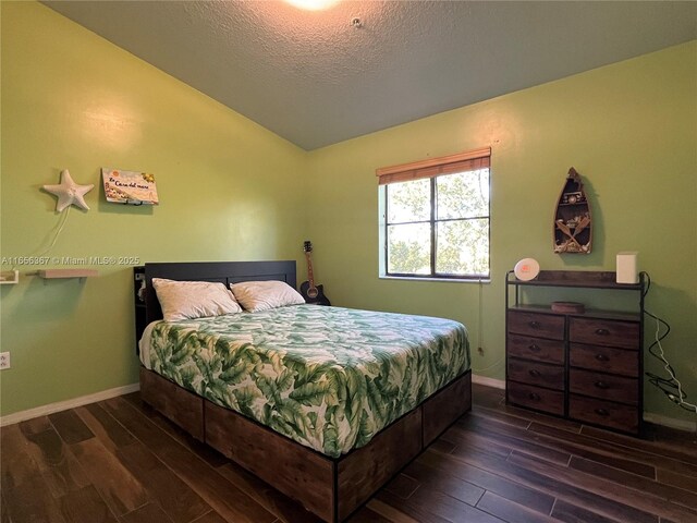 bedroom featuring lofted ceiling, dark hardwood / wood-style flooring, and a textured ceiling