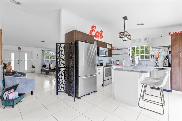 kitchen featuring lofted ceiling, a healthy amount of sunlight, a kitchen island, and stainless steel appliances