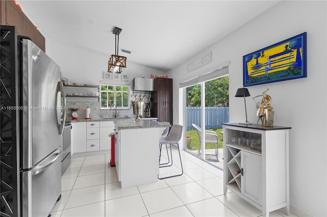 kitchen with plenty of natural light, a breakfast bar, stainless steel fridge, and white cabinets