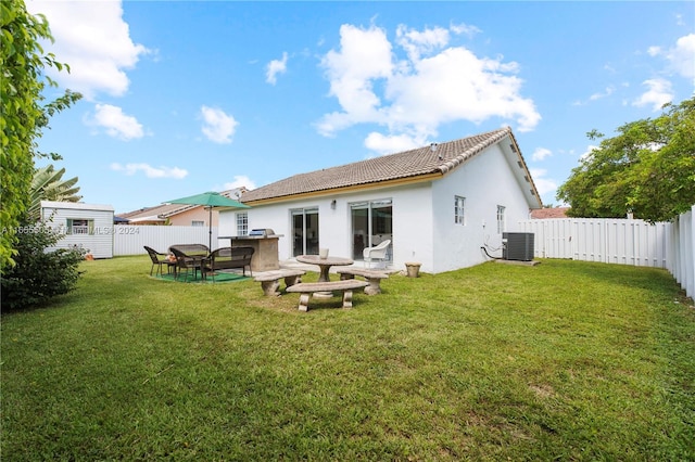 rear view of house with central AC and a yard