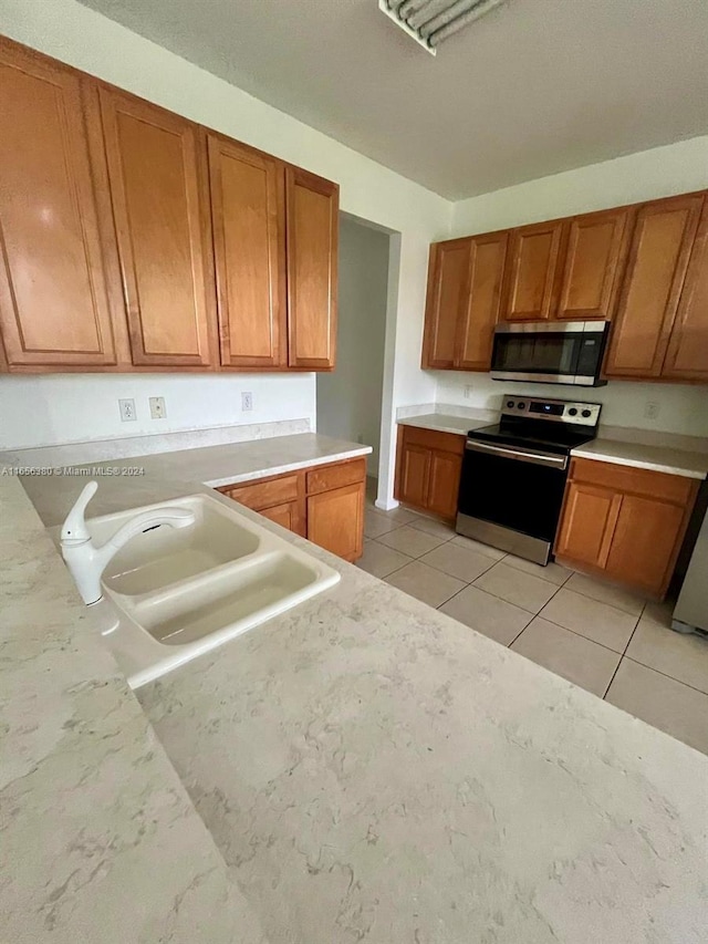 kitchen with sink, light tile patterned floors, and appliances with stainless steel finishes