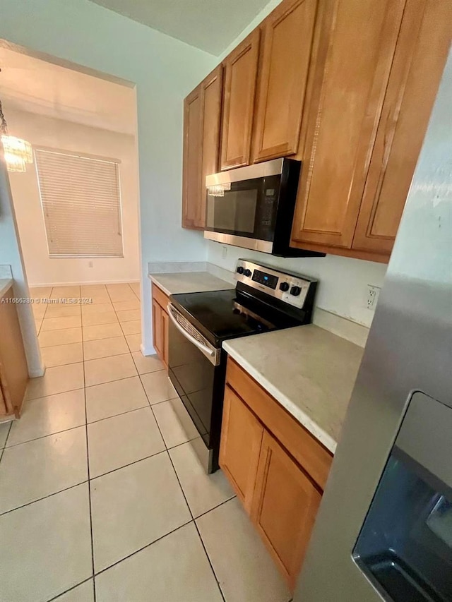 kitchen with light tile patterned floors, black / electric stove, and a notable chandelier