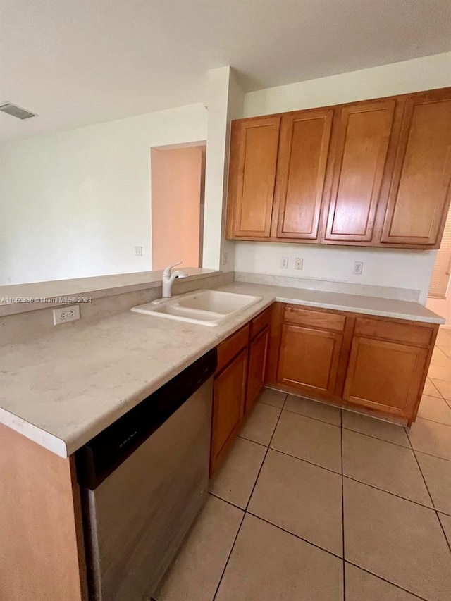 kitchen with kitchen peninsula, sink, light tile patterned floors, and stainless steel dishwasher