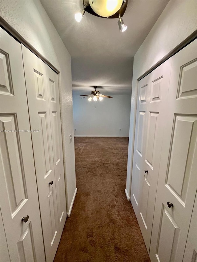 hall with dark colored carpet