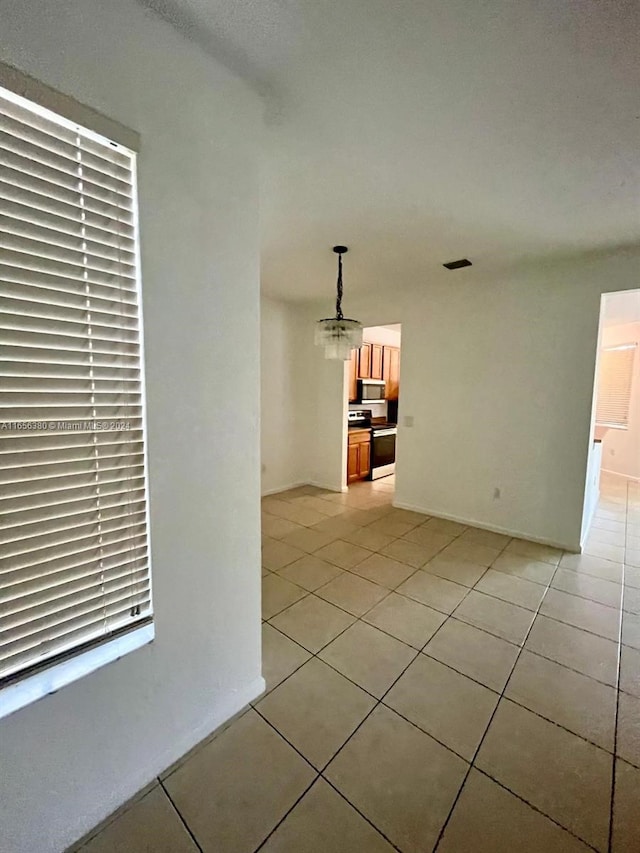 spare room featuring light tile patterned floors and an inviting chandelier