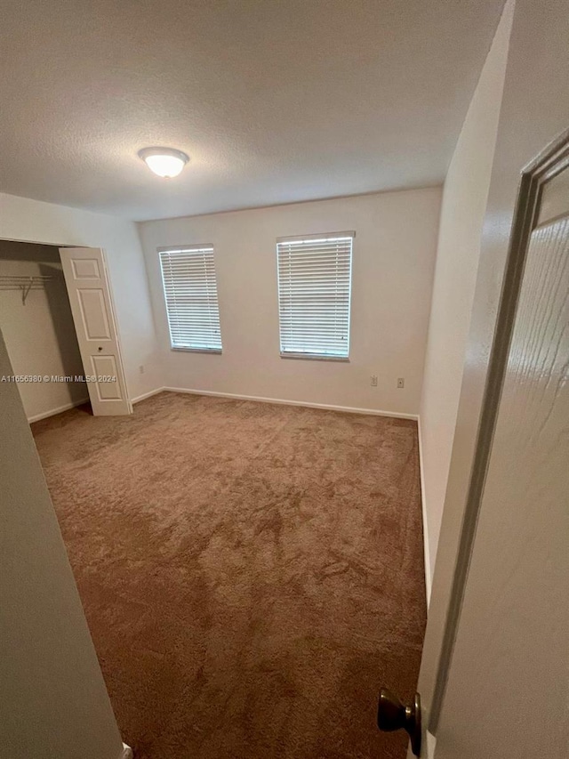 unfurnished bedroom featuring carpet flooring, a closet, and a textured ceiling