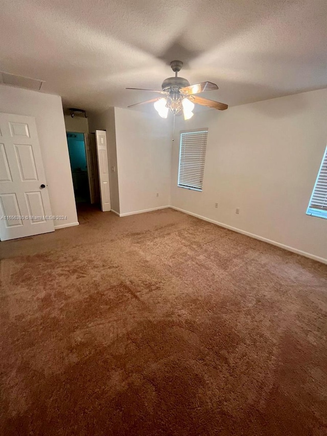 carpeted spare room featuring ceiling fan and a textured ceiling