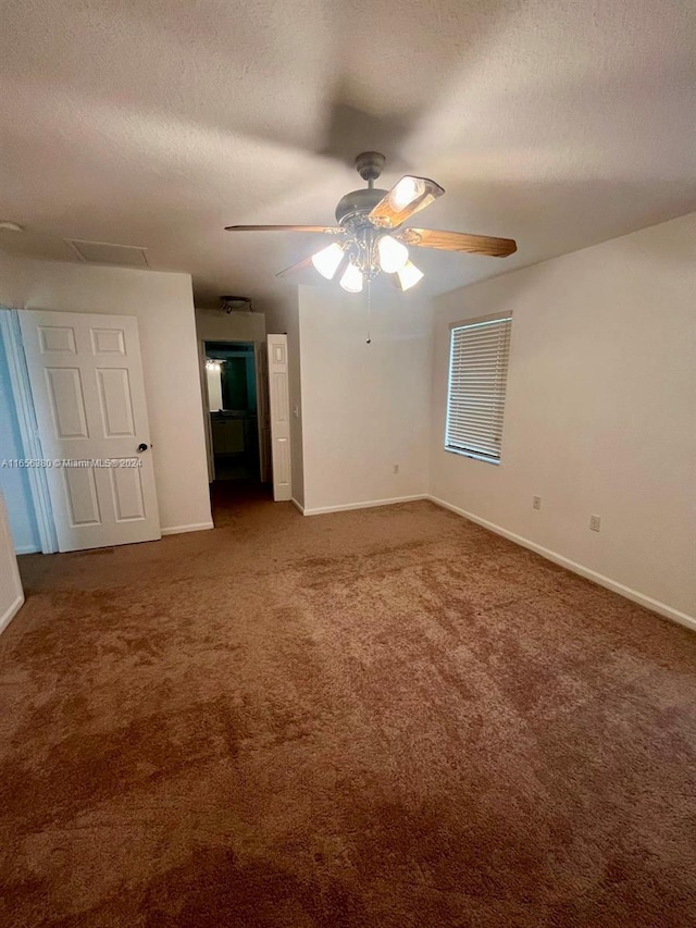 unfurnished bedroom featuring ceiling fan, a textured ceiling, and dark colored carpet