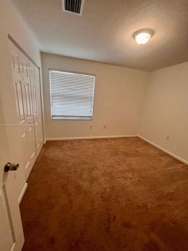 carpeted empty room with a textured ceiling