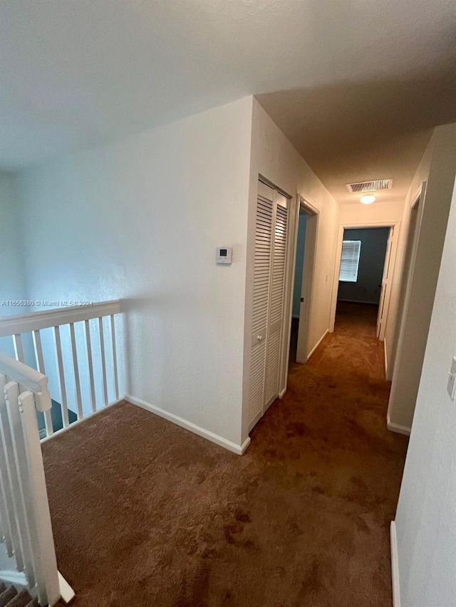 hallway featuring dark colored carpet